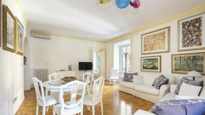 Un'ampia zona giorno con un divano bianco, un tavolo da pranzo con sedie e una televisione.