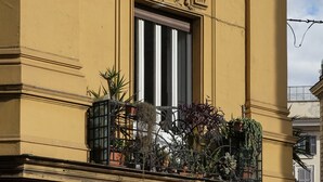 Un edificio giallo con balconi decorati, ampie finestre e piante in vaso.