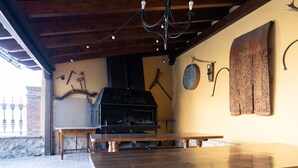 An outdoor patio with a wooden table and benches, a brick floor, and a rustic wooden ceiling. - Casa del Agüelo: Apartment Teruel (5 people) (Cella)