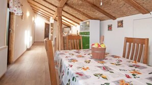 A rustic kitchen with wooden beams, a dining table with a floral tablecloth, and a fruit basket. - Tre Rose by Interhome (Opatija/Zvoneće)