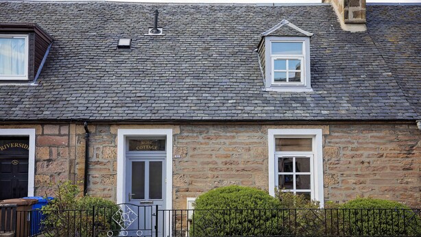 A stone building with two doors, one labeled "Riverside" and the other "Rose Cottage."