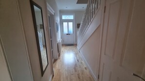A hallway with wooden flooring, white walls, and a door at the end.