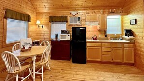 A compact kitchen with wooden walls and a dining area.