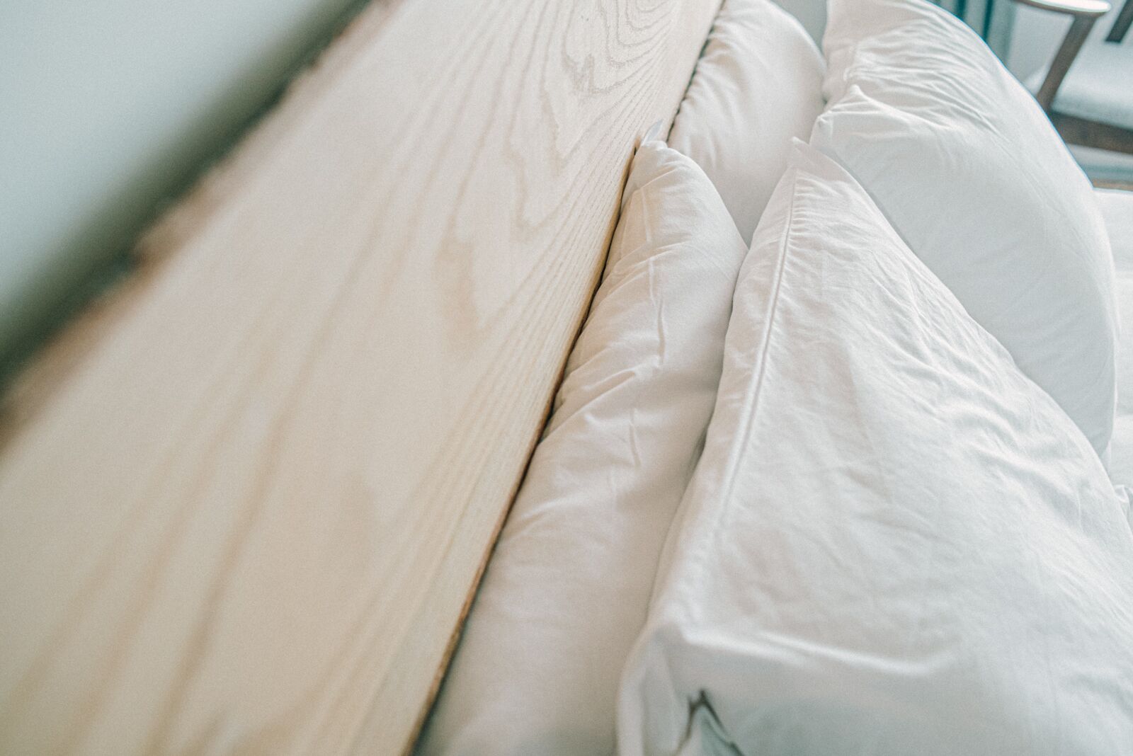 A bed with a wooden headboard and white pillows.