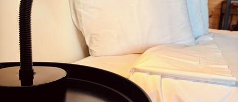 A bed with white bedding and a black desk lamp.