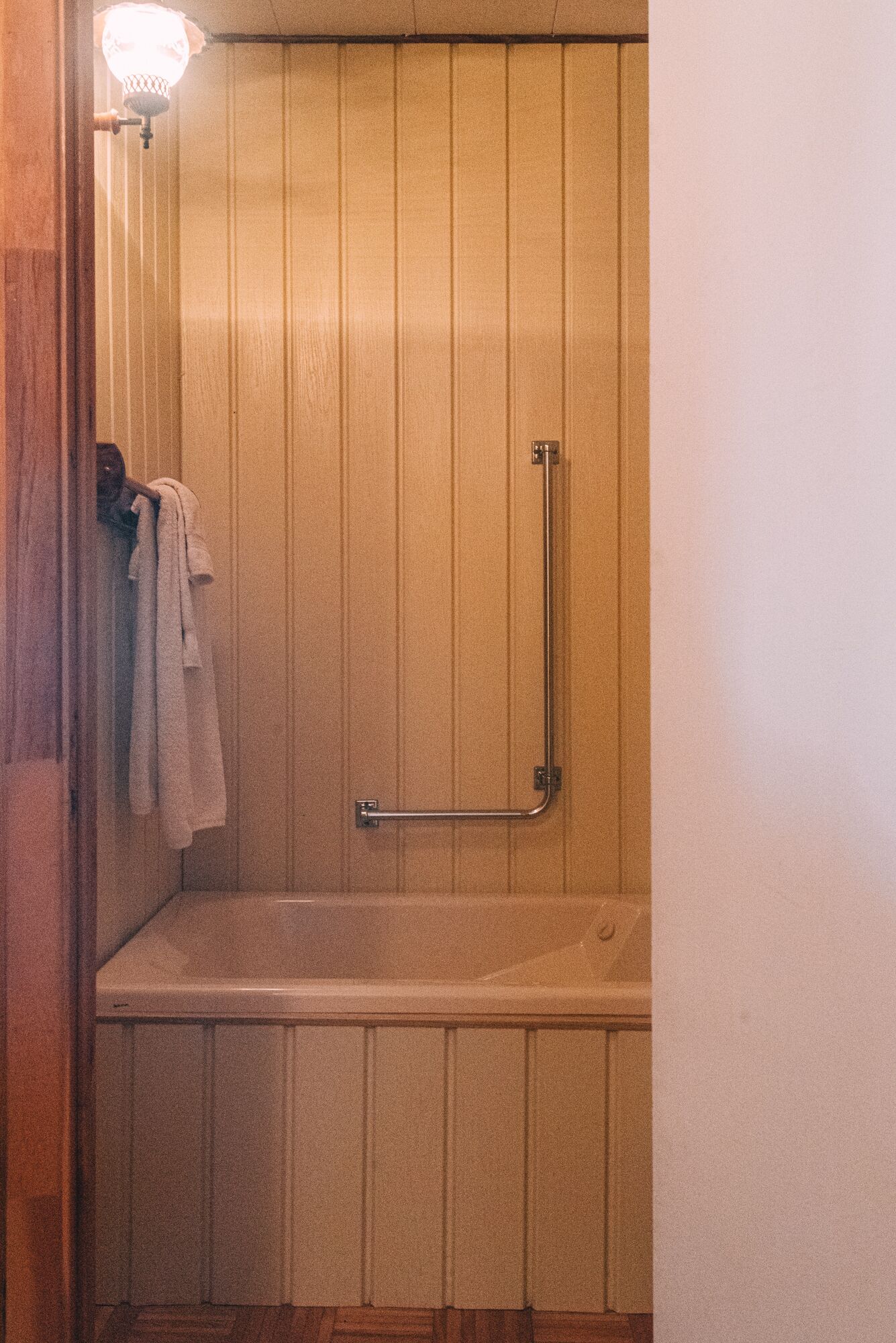 A wooden-paneled bathroom with a shower stall, a towel rack, and a light fixture.