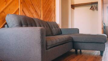 A gray sectional sofa in a room with wooden walls and a wooden floor.
