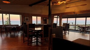 A cozy restaurant with wooden interiors, large windows offering ocean views, and a rustic ambiance.