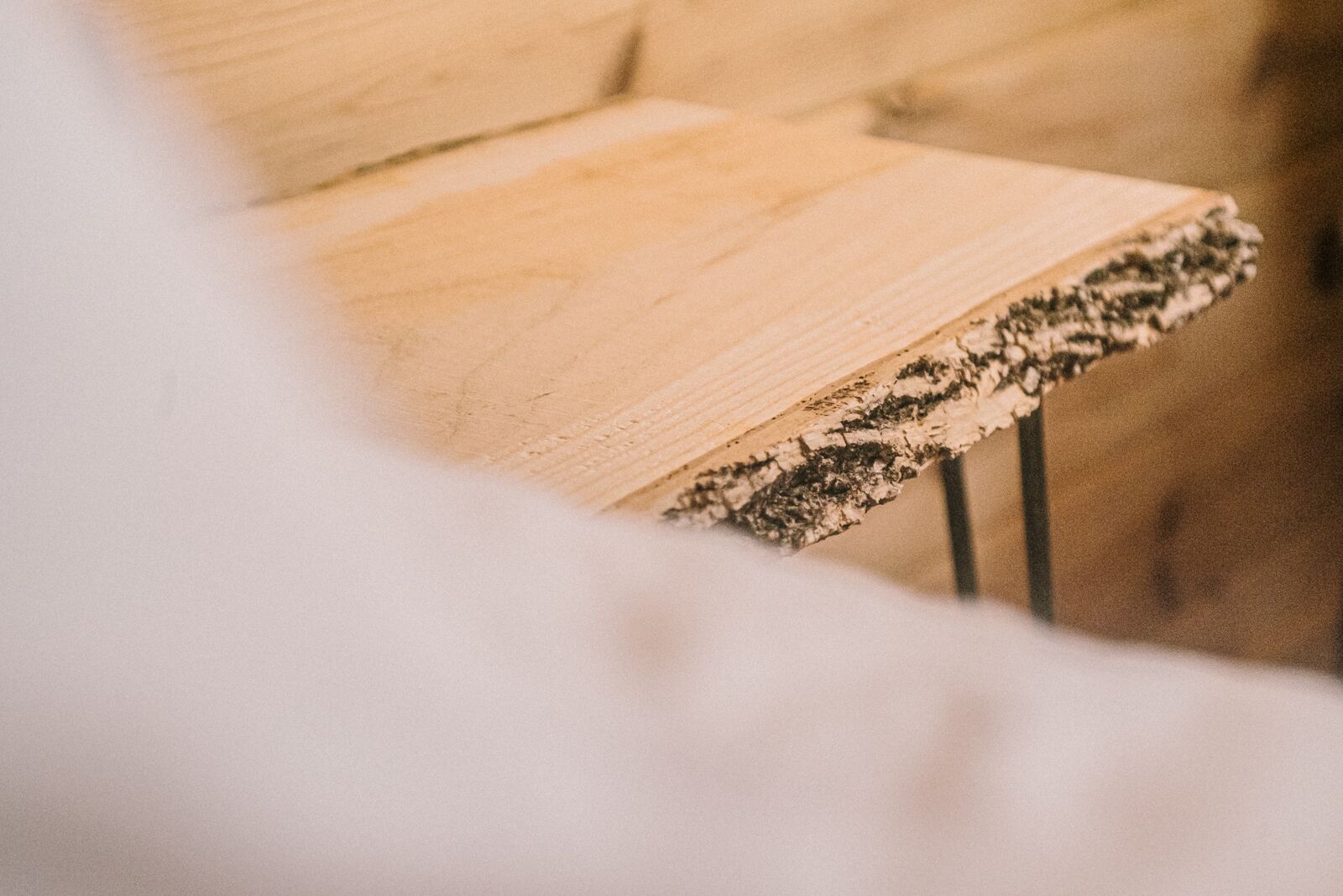 A close-up of a wooden table with a textured edge, likely made of birch or similar wood, with a natural finish.