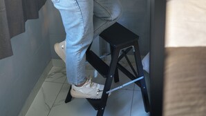 A person standing on a stool reaching for a bed in a narrow room with a tiled floor. - Lion University & Youth Hostel Milano (Milan)