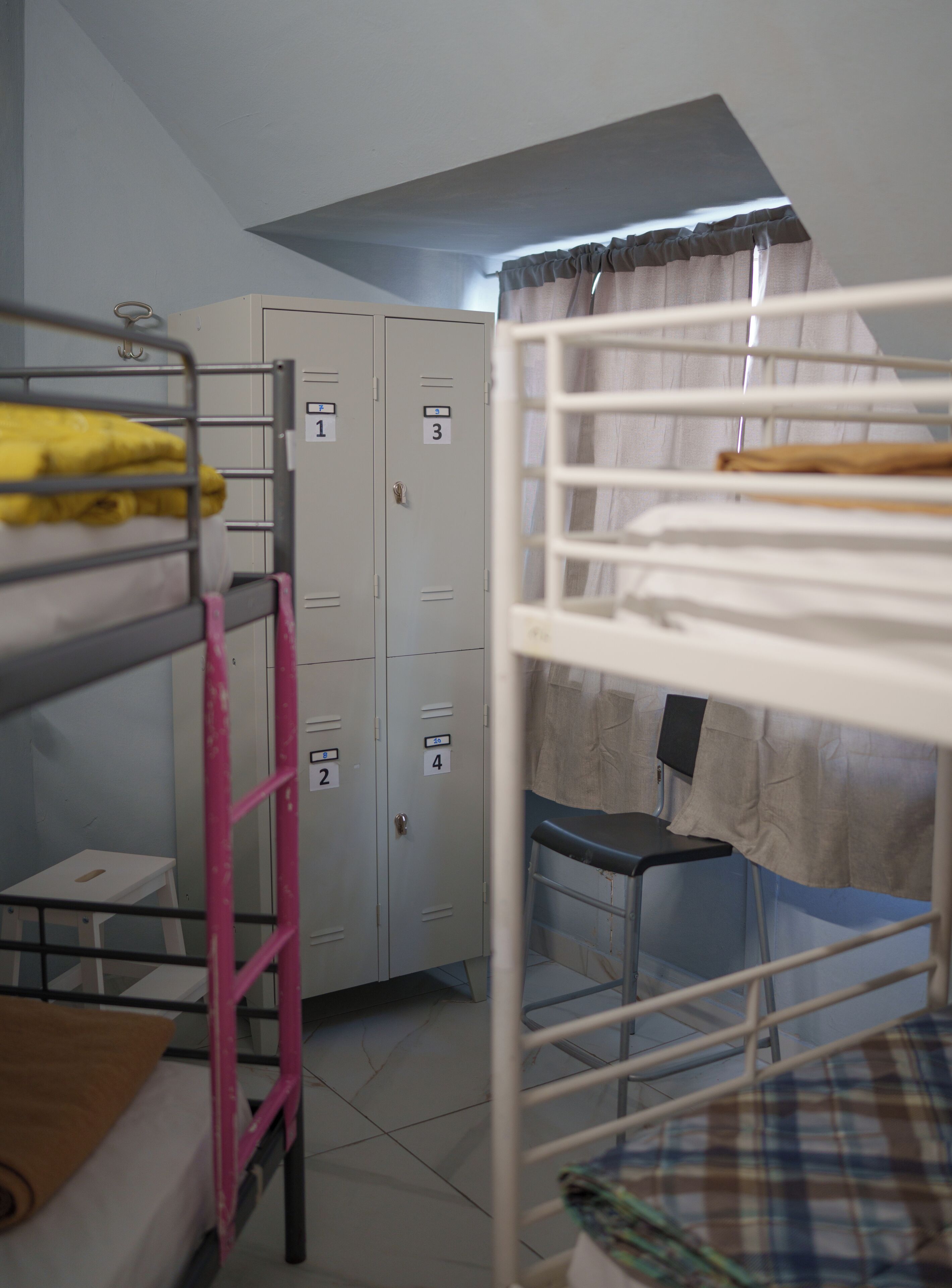 A dormitory room with bunk beds, a desk, and lockers.