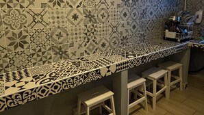 A kitchen with a patterned backsplash, white bar stools, and a coffee machine on the counter. - Lion University & Youth Hostel Milano (Milan)