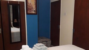 A bedroom with a bed, a mirror, a painting, and a door. - Just Like Home, New Kingston (New Kingston)