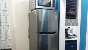 A compact kitchen with a stainless steel refrigerator, a microwave, and a sink. - Just Like Home, New Kingston (New Kingston)