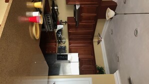 A kitchen with wooden cabinets, a stainless steel refrigerator, a stove, and a microwave. - Bayfront Condo with Boat Slip (Panacea)