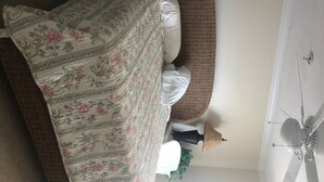 A bed with a floral bedspread, a brown woven headboard, and a white pillow. - Bayfront Condo with Boat Slip (Panacea)