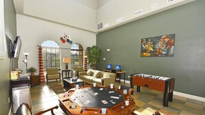 A spacious room with a round table for games, a foosball table, and a painting on the wall. - Bella Piazza 288924 (Davenport)