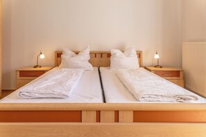 Un letto matrimoniale con testiera e pediera in legno, due comodini con lampade e un termosifone a parete.