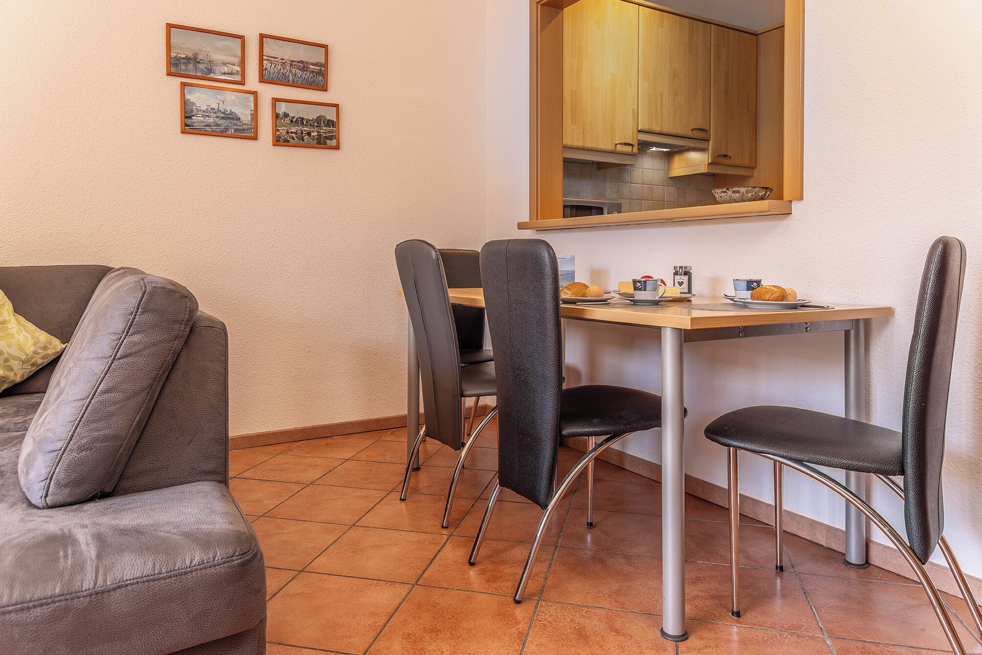 Un espacio habitable compacto con sofá, mesa de comedor, sillas y zona de cocina.