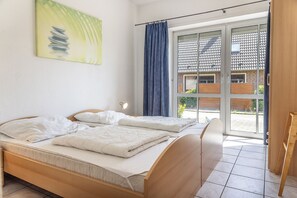 Una camera da letto con un letto, una lampada da comodino, una finestra con vista su un edificio e un quadro appeso al muro.