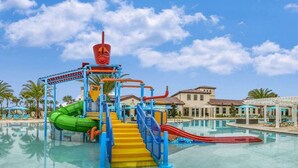 A water park with slides and a pool area, surrounded by palm trees and buildings. - Luxurious Vacation Townhome With Private Pool (Kissimmee)