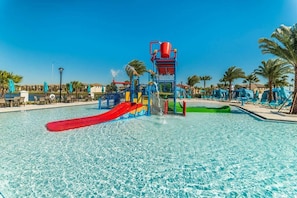 Um parque aquático com uma piscina grande, um escorrega vermelho e uma estrutura de recreação aquática.