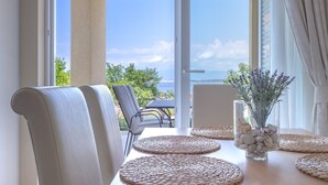 A dining area with a table set for two, featuring woven placemats and a vase with decorative stones.