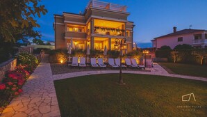 A two-story villa with a balcony, outdoor seating area, and a well-lit entrance.
