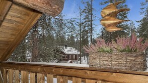 A wooden deck with a view of a cabin surrounded by trees and a decorative log structure.