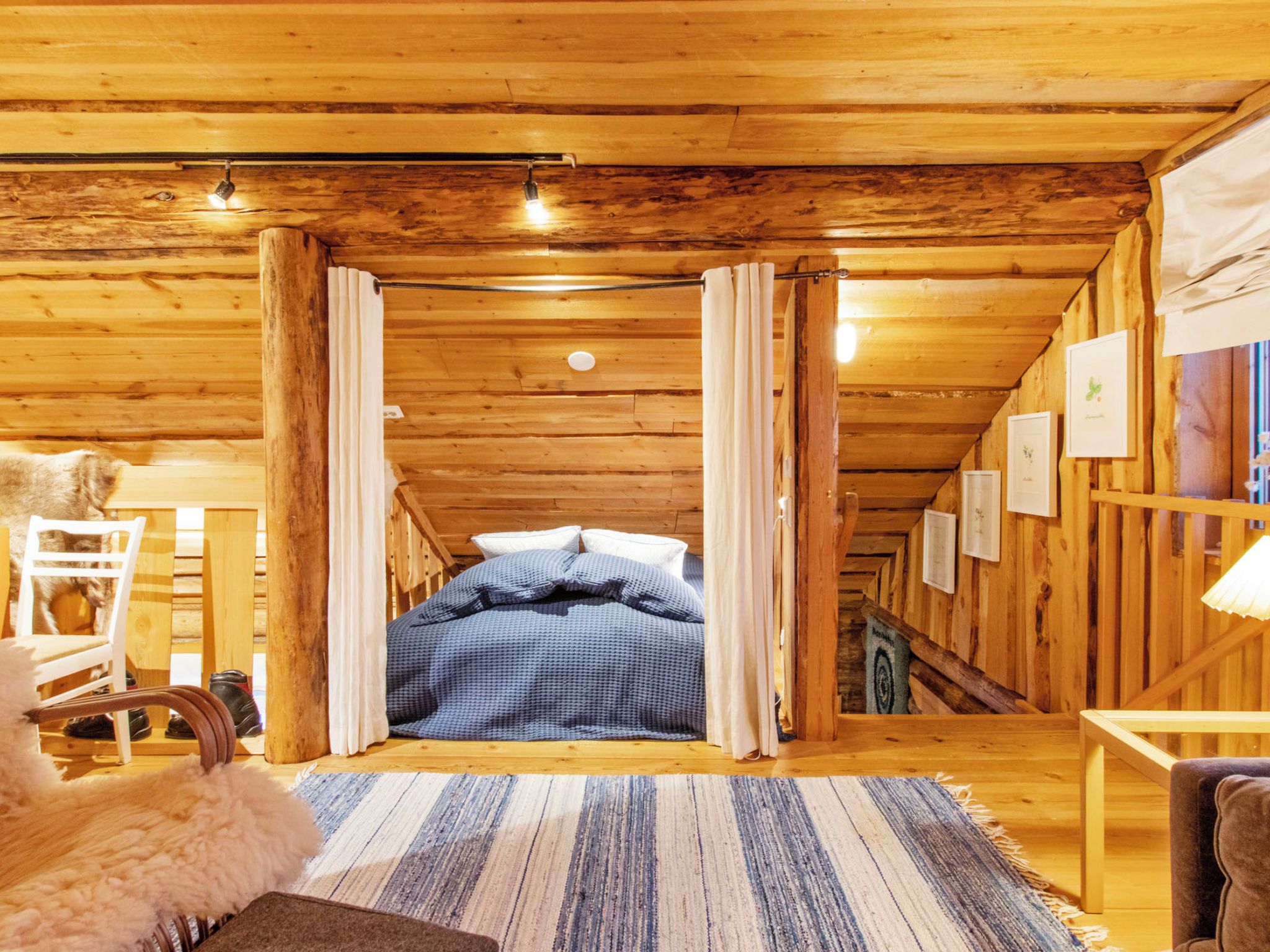 Una habitación acogedora de madera con una cama, una silla y una alfombra.