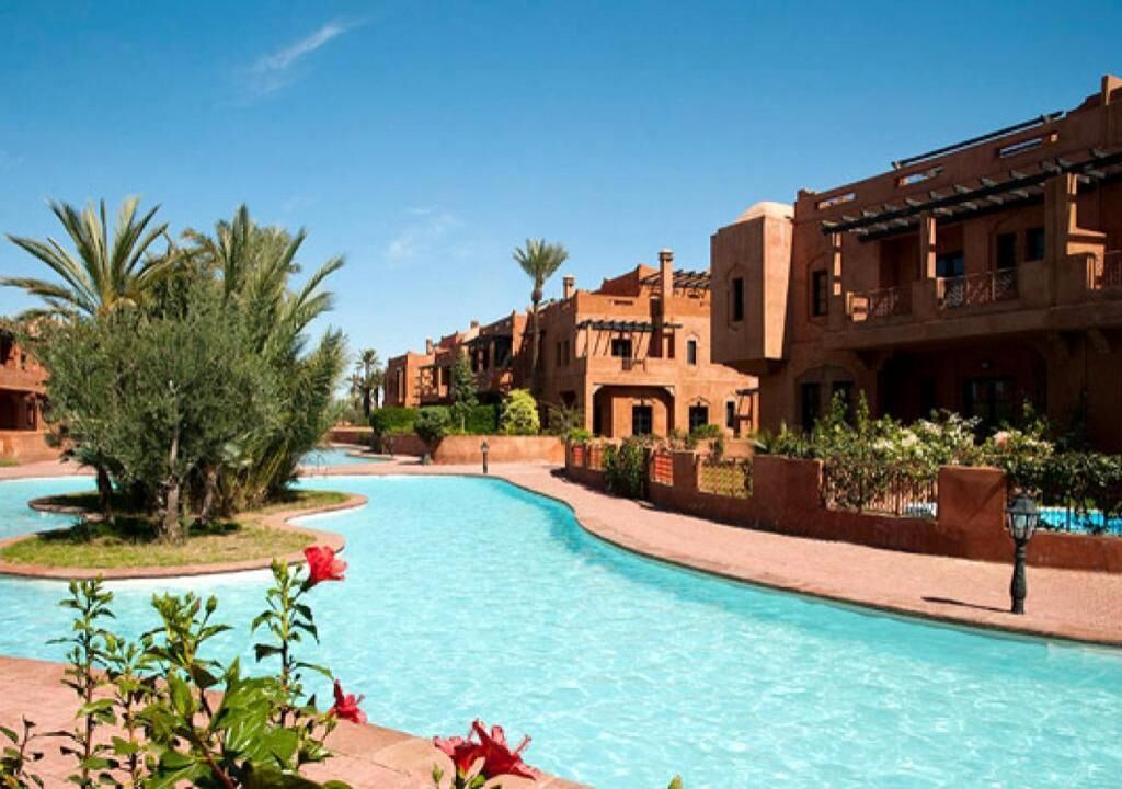A pool area with a curved design, surrounded by buildings with traditional architecture.
