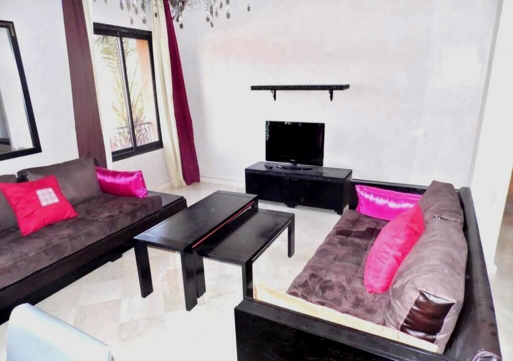 A modern living room with a sofa set, a coffee table, and a flat-screen TV mounted on the wall.