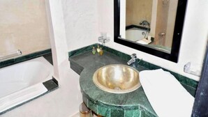 Een badkamer met een badkuip, een wastafel met spiegel en een groen marmeren aanrechtblad.