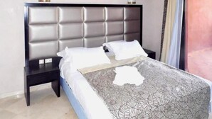 Een bed met een grijs beklede hoofdbord, twee nachtkastjes en een bedsprei met dessin.