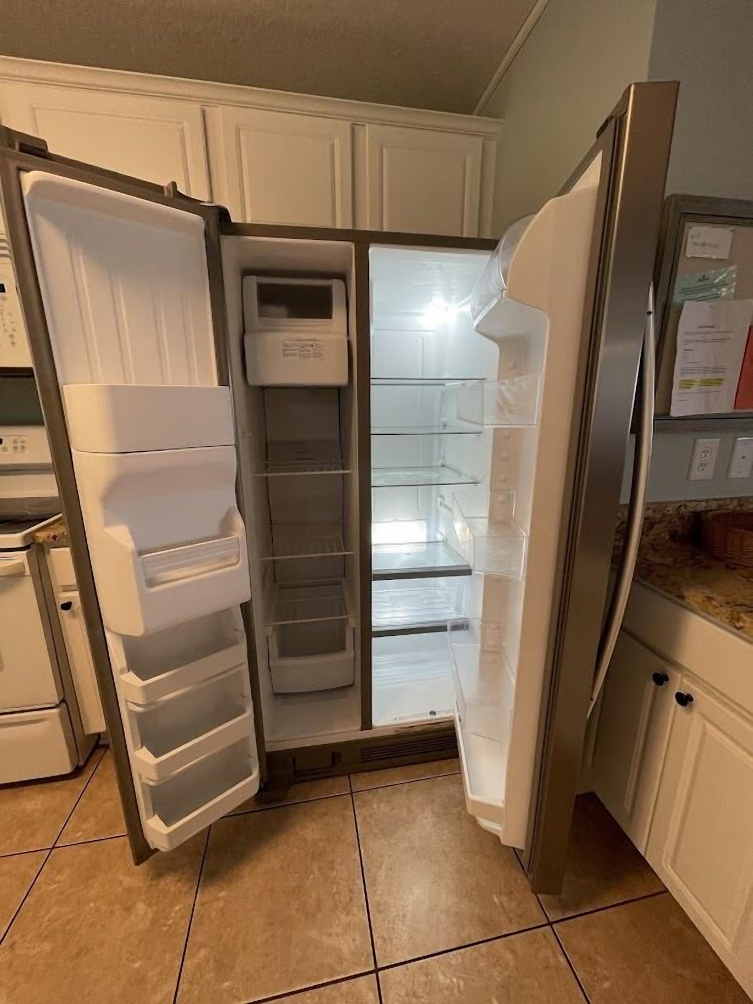 A kitchen with white cabinets, a stainless steel refrigerator, and a tiled floor.