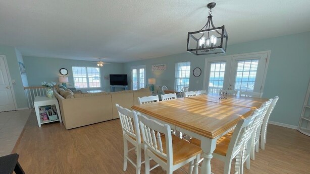 Un salón amplio con una mesa de comedor de madera y sillas blancas, un sofá y un televisor.