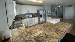 Una cocina moderna con armarios blancos, electrodomésticos de acero inoxidable y encimeras de granito.