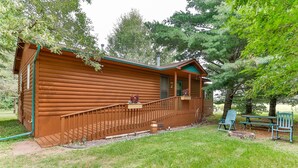 A wooden cabin with a porch, a small deck, and outdoor seating. - Cozy and comfortable accommodations in picturesque country setting (Hinckley)
