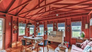 A cozy cabin interior with wooden walls, a dining area with a table and chairs, a sofa, and a kitchen area with a stove and cabinets. - Cozy and comfortable accommodations in picturesque country setting (Hinckley)