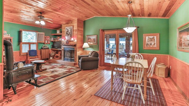 A cozy living room with a fireplace, wooden floors, and a dining area. - Cozy and comfortable accommodations in picturesque country setting (Hinckley)