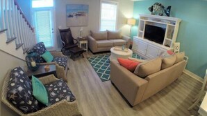 Una sala de estar con sofá, sillón y mueble para televisor.