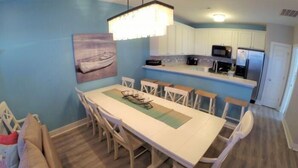 Cocina compacta con armarios blancos, microondas y refrigerador.