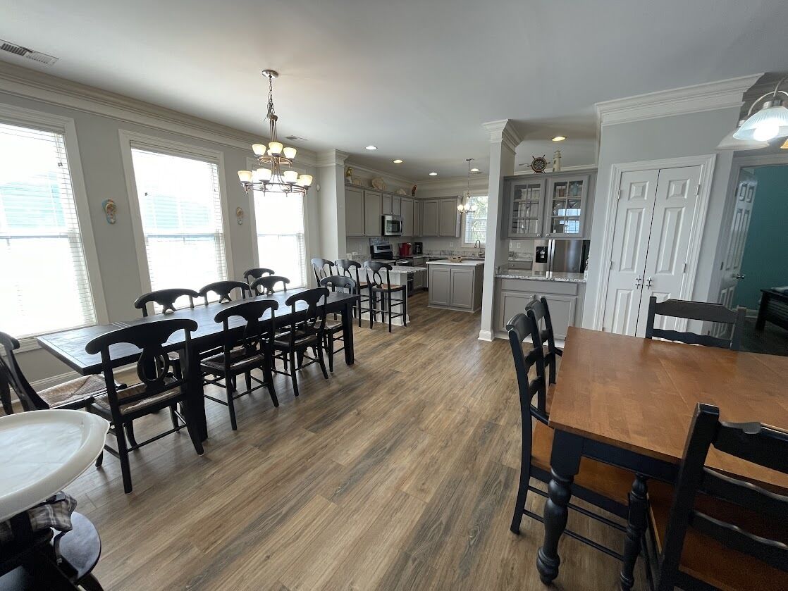 A spacious kitchen with a central island, wooden dining table, and chairs.