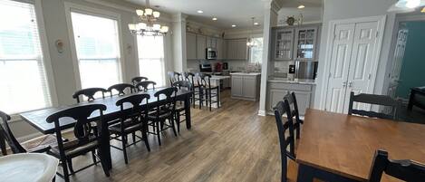 A spacious kitchen with a central island, wooden dining table, and chairs.