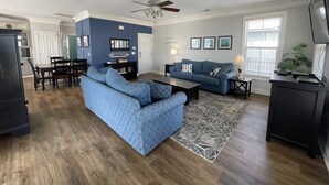 A living room with a blue sofa, a coffee table, a rug, and a ceiling fan. - Nana's Nook - Second Row in Garden City Beach (Garden City)