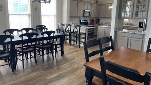 A spacious kitchen with a dining area, featuring a wooden table and chairs, a built-in oven, and a microwave. - Nana's Nook - Second Row in Garden City Beach (Garden City)