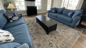 A living room with two blue sofas, a black coffee table, and a patterned rug. - Nana's Nook - Second Row in Garden City Beach (Garden City)