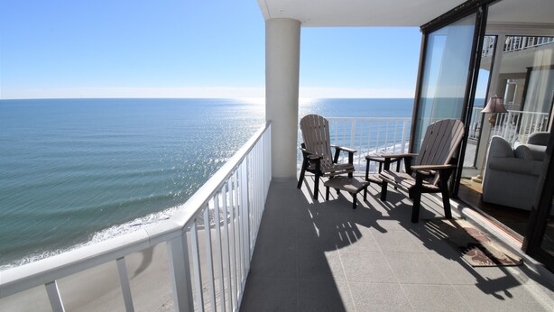 A balcony with a view of the ocean, two wooden chairs, and a small table. - One Ocean Place 1104 - Oceanfront Condominium in Garden City Beach (Garden City)