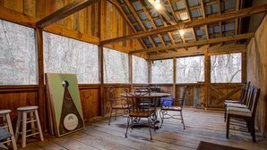 Una cabaña de madera rústica con comedor, que incluye una mesa redonda y sillas de metal.