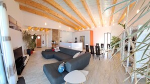 A modern living room with a sectional sofa, a small white table, and a kitchen area in the background.